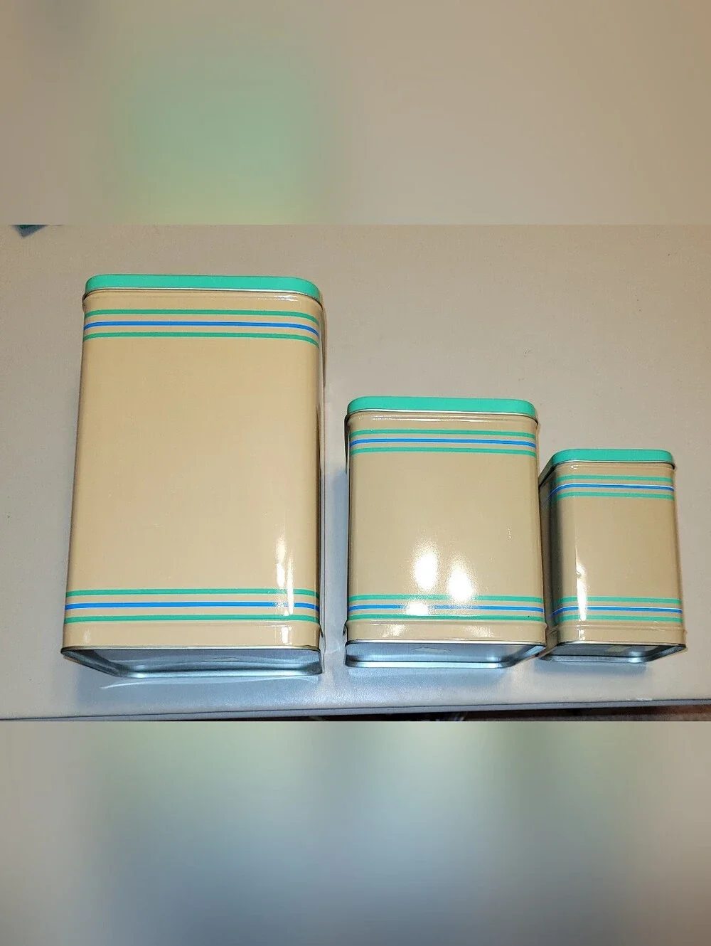 LASLO - Set of 3 Nesting Tan Metal Canisters with Green Lids and Stripes.